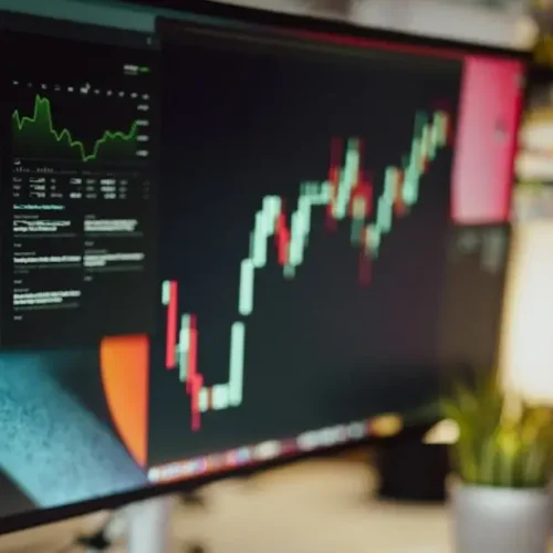 a person writing on a piece of paper next to a computer monitor